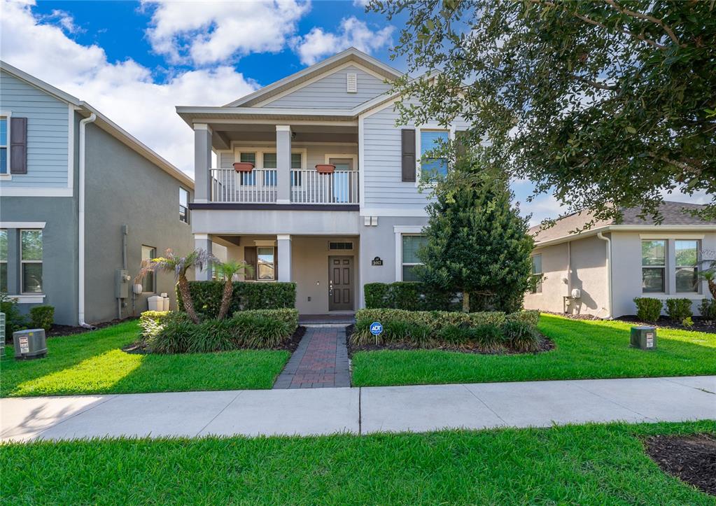 A two-story house with a front porch, a balcony, and a brick walkway — 9463 KOMIKA LANE, WINTER GARDEN, FL