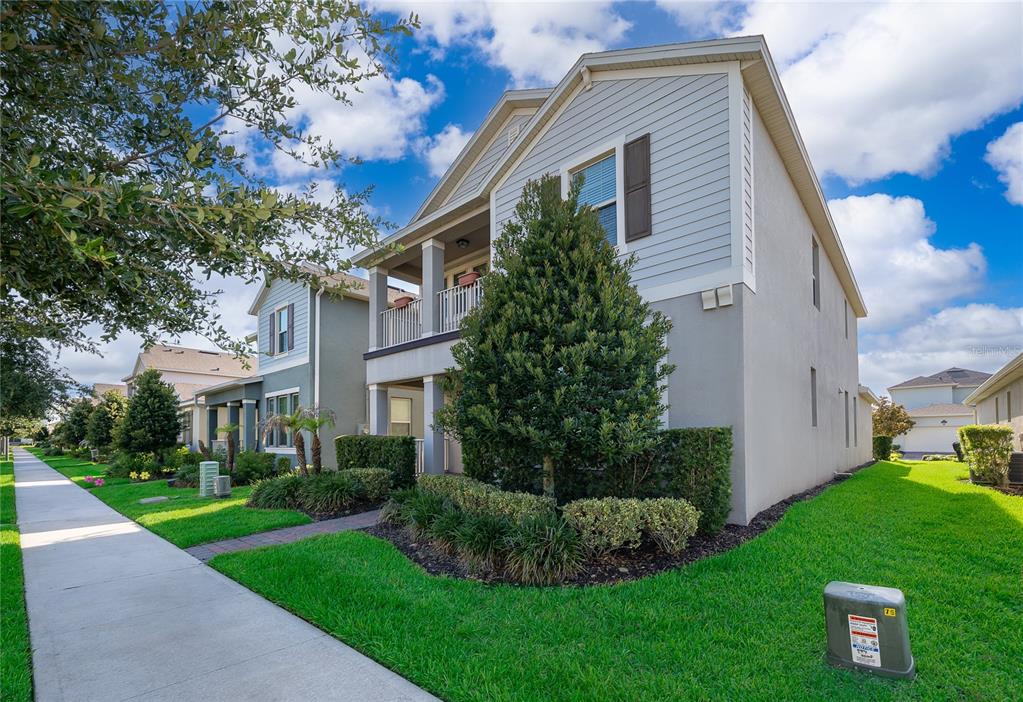 A two-story house with light gray siding, a front balcony, and a manicured lawn — 9463 KOMIKA LANE, WINTER GARDEN, FL