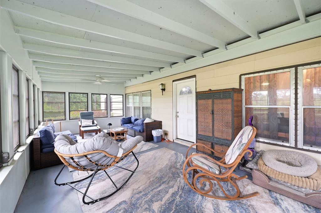 A sunroom features a white ceiling, large windows, a rocking chair, and outdoor-style furniture — 7663 CR 247, LAKE PANASOFFKEE, FL