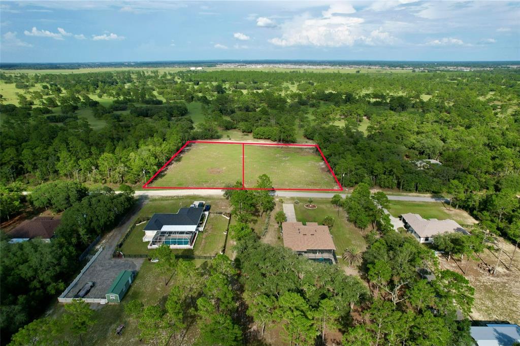 An aerial view shows two adjacent rectangular vacant lots outlined in red near residential homes — 0 SW 121 TERRACE SW, DUNNELLON, FL