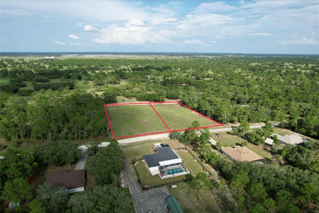An aerial view shows two adjacent cleared rectangular lots outlined in red near a house — 0 SW 121 TERRACE SW, DUNNELLON, FL