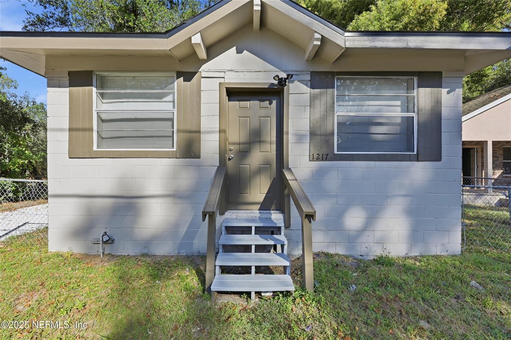 The exterior of a small, single-story house features a concrete block facade and front stairs — 1217 W 29TH STREET, JACKSONVILLE, FL
