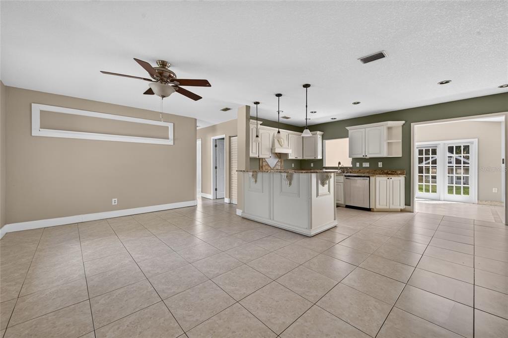 An open-concept kitchen and dining area features tile flooring, a central island, and white cabinetry — 1145 GEORGE ANDERSON STREET, ORMOND BEACH, FL