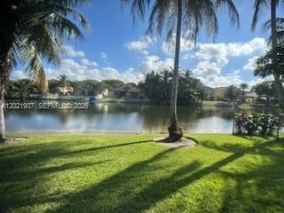 A grassy backyard overlooks a lake with palm trees and houses in the distance — 5003 SW 163rd Ave, Miramar FL 33027, MIRAMAR, FL