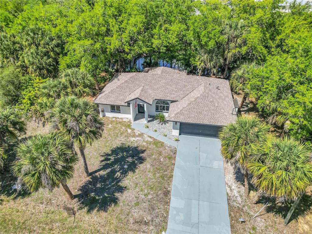 An aerial view of a single-story house with a gray roof and a concrete driveway — 26140 HAPSBURG ROAD, PUNTA GORDA, FL