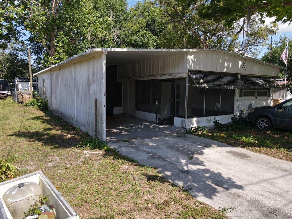 A single-story mobile home features a metal carport, a screened-in porch, and a concrete driveway — 28814 HUBBARD STREET, LEESBURG, FL