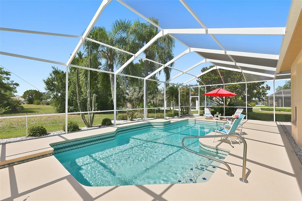 A screened-in swimming pool with a patio and lounge chairs in a backyard setting — 2224 PLATINUM DRIVE, SUN CITY CENTER, FL