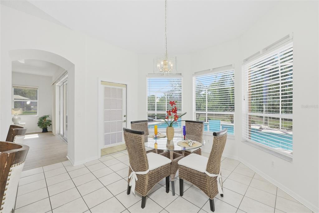 A dining area with a glass table, wicker chairs, tile floors, and a pool view — 2224 PLATINUM DRIVE, SUN CITY CENTER, FL