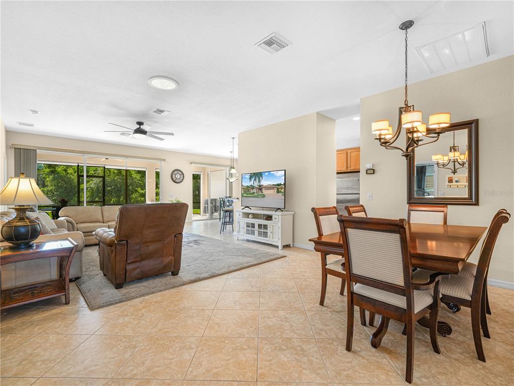 An open-concept living and dining area features tile flooring, a ceiling fan, and sliding doors — 5337 HOGAN LANE, WINTER HAVEN, FL