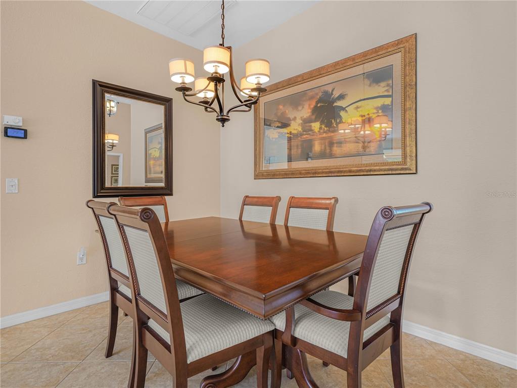 A dining room features a wooden table, four chairs, a chandelier, a mirror, and artwork — 5337 HOGAN LANE, WINTER HAVEN, FL