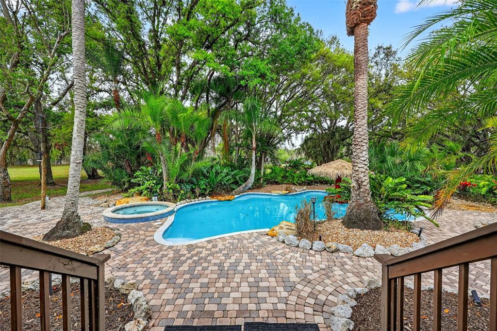 A backyard features a swimming pool, a hot tub, and a brick patio surrounded by trees — 6888 MYAKKA VALLEY TRL, SARASOTA, FL