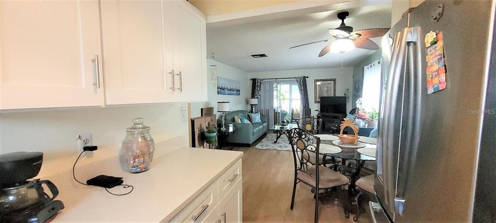 A kitchen with white cabinets and a coffee maker overlooks a dining and living area — 9 VILLA VILLAR COURT UNIT N/A, DELAND, FL