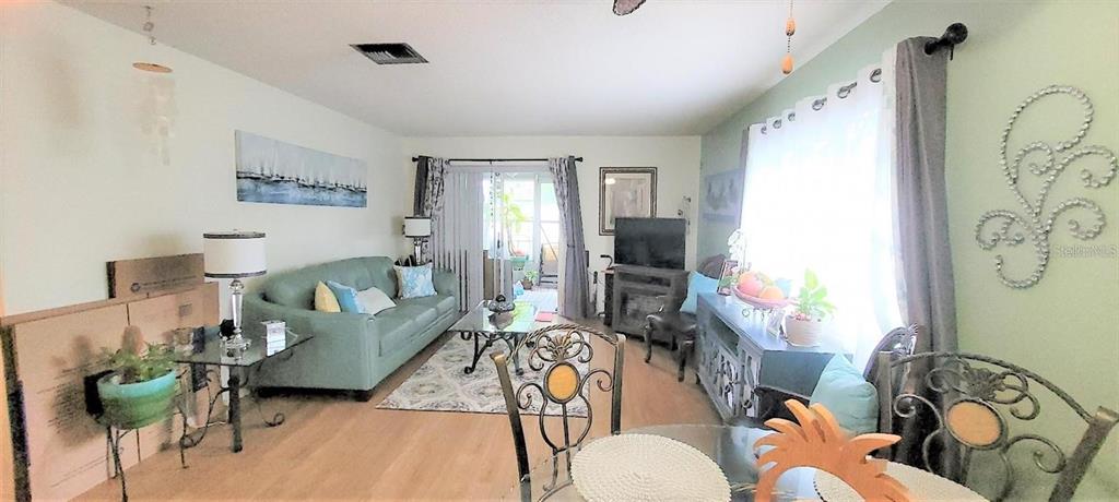 A living room features a light green sofa, wood-look flooring, and a glass-topped dining table — 9 VILLA VILLAR COURT UNIT N/A, DELAND, FL