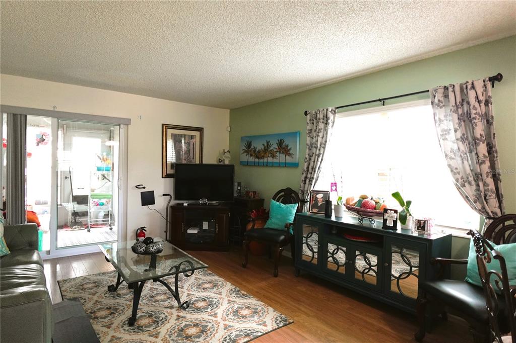 A living room features a glass coffee table, a television, and a teal media console — 9 VILLA VILLAR COURT UNIT N/A, DELAND, FL
