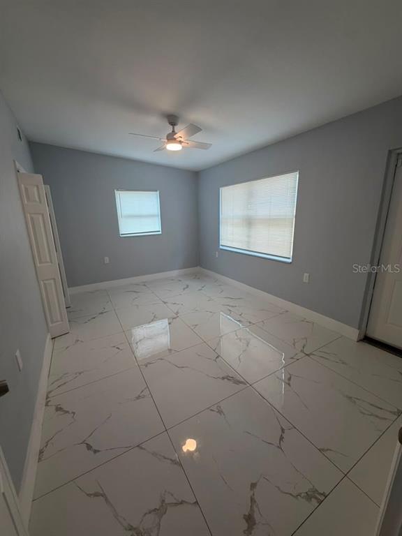 An empty room features light gray walls, white marble-patterned tile flooring, and a ceiling fan — 2615 E 23RD AVENUE, TAMPA, FL