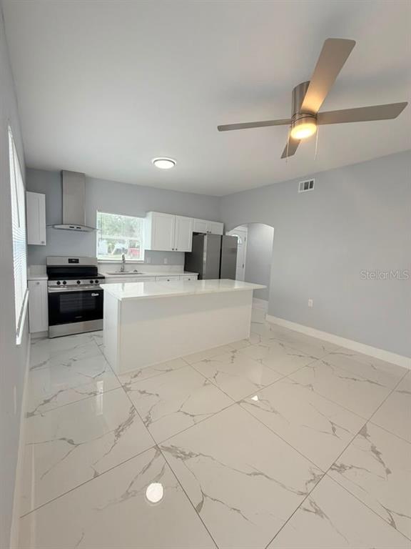 A modern kitchen features white cabinets, stainless steel appliances, a center island, and marble-look flooring — 2615 E 23RD AVENUE, TAMPA, FL