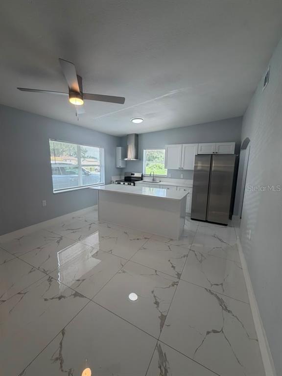 A kitchen features white cabinets, a central island, stainless steel appliances, and marble-patterned tile flooring — 2615 E 23RD AVENUE, TAMPA, FL