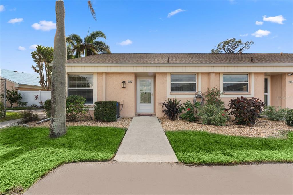 A single-story peach-colored house with a concrete walkway leading to the front door — 6250 7TH AVENUE W UNIT 6250, BRADENTON, FL