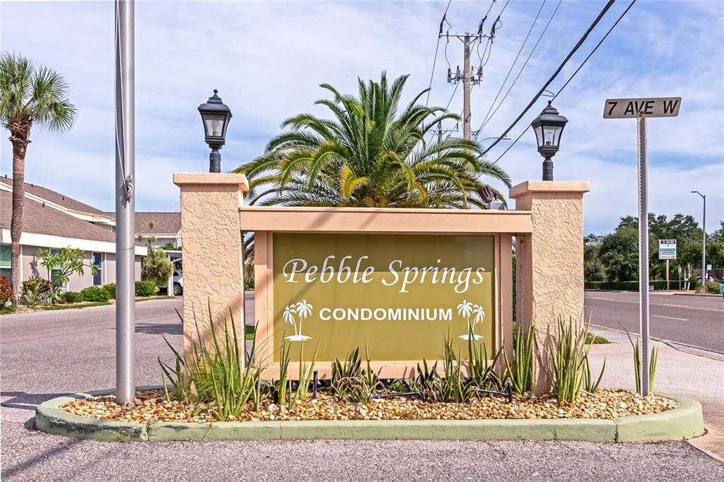A sign for Pebble Springs Condominium stands at the entrance of a residential property — 6250 7TH AVENUE W UNIT 6250, BRADENTON, FL