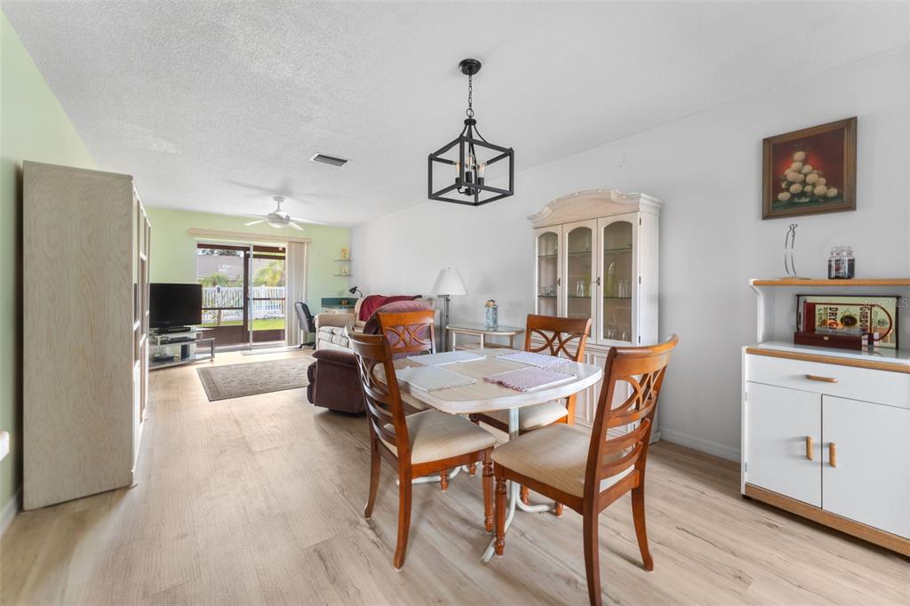 A dining area with a wooden table and chairs sits in front of a living room — 6250 7TH AVENUE W UNIT 6250, BRADENTON, FL