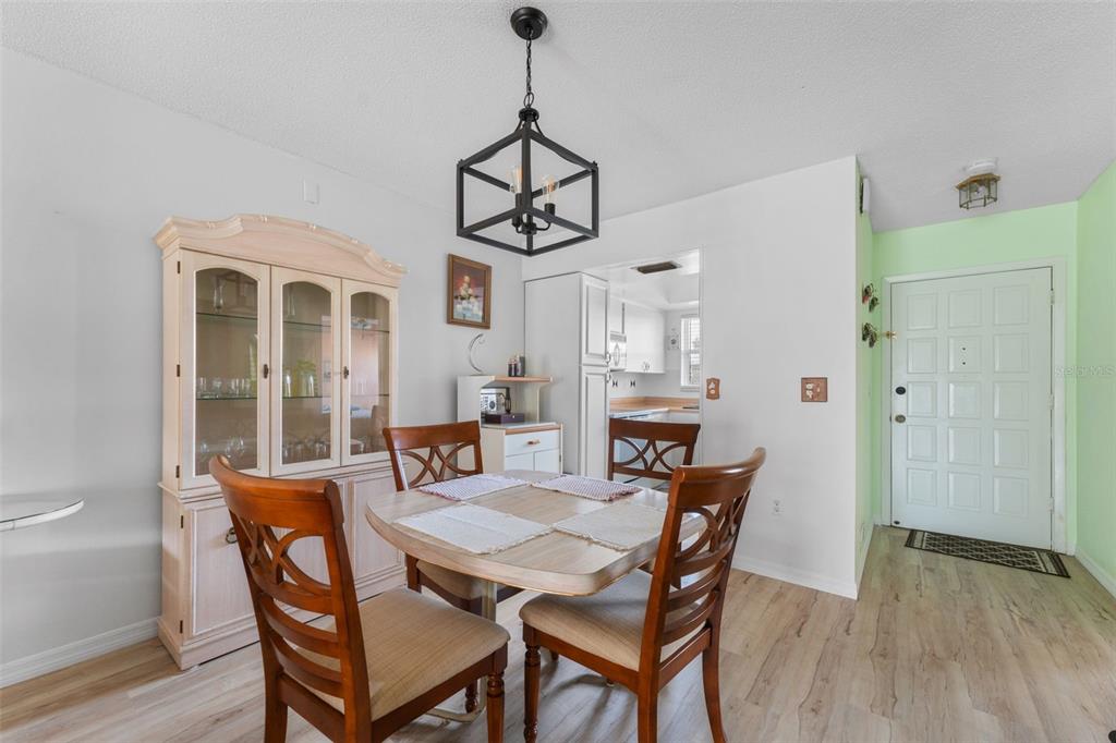 A dining area features a wooden table, four chairs, a hutch, and a modern light fixture — 6250 7TH AVENUE W UNIT 6250, BRADENTON, FL