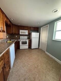 A kitchen features wood cabinets, white appliances, a tiled floor, and a window — 421 NE 14th Ave # 401, Hallandale Beach FL 33009, HALLANDALE BEACH, FL