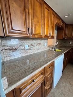 A kitchen features wood cabinets, granite countertops, and a white dishwasher — 421 NE 14th Ave # 401, Hallandale Beach FL 33009, HALLANDALE BEACH, FL