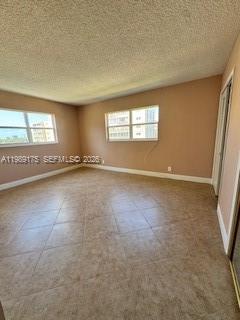 An empty room with beige walls, tile flooring, and two windows overlooking a city view — 421 NE 14th Ave # 401, Hallandale Beach FL 33009, HALLANDALE BEACH, FL