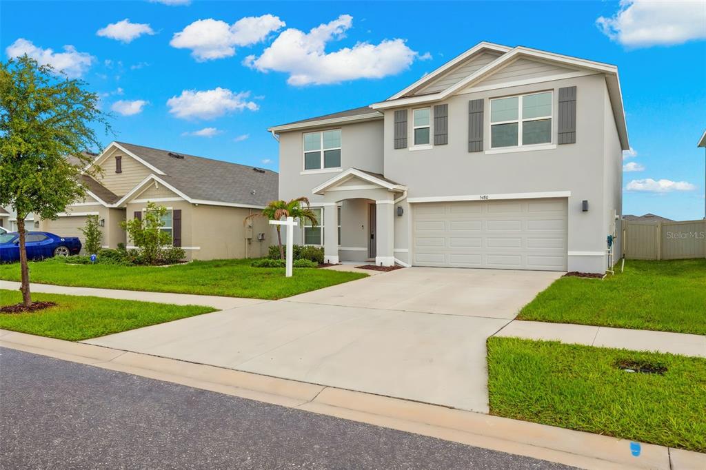 A two-story suburban house with a gray exterior, a two-car garage, and a concrete driveway — 5480 FLINT HILLS DRIVE, WIMAUMA, FL