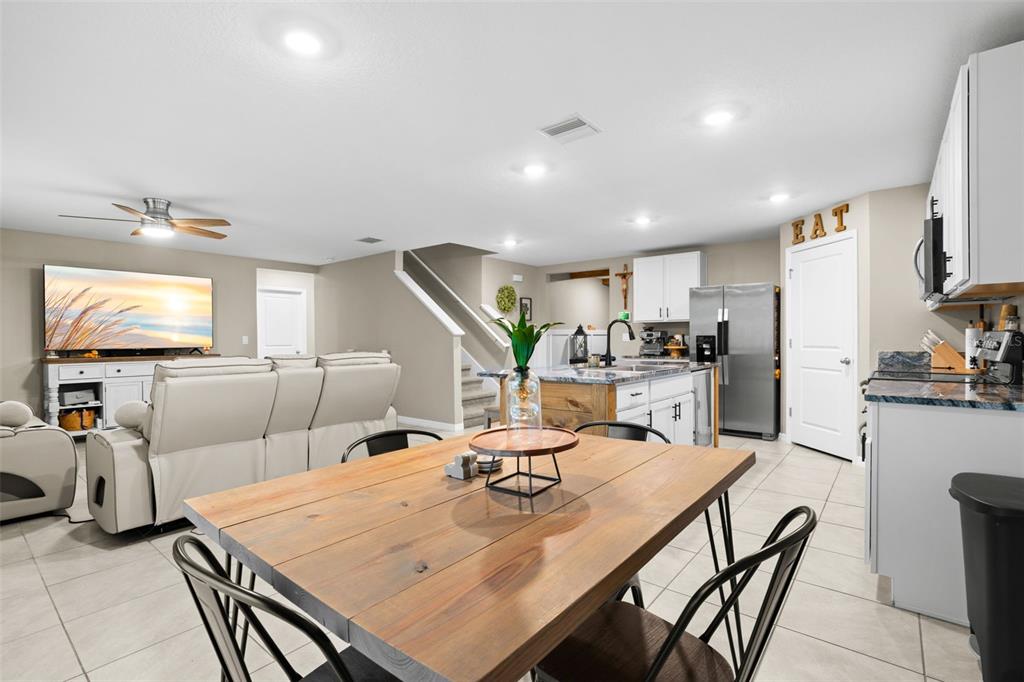 An open-concept kitchen and living area featuring a wooden dining table and tile flooring — 5480 FLINT HILLS DRIVE, WIMAUMA, FL