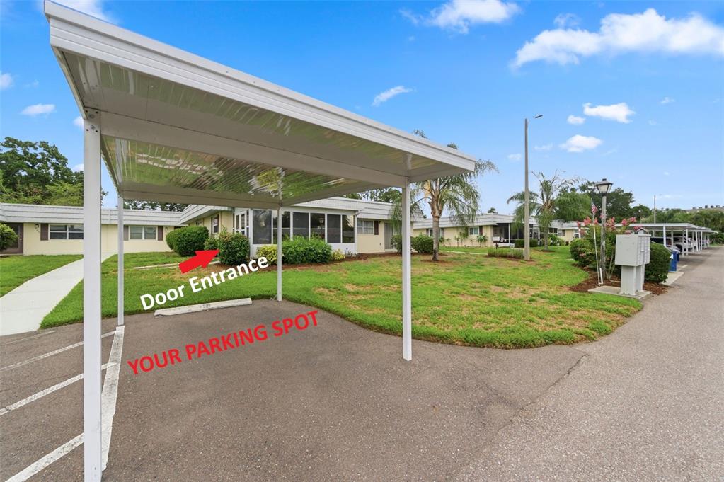 A covered parking carport sits in front of a single-story apartment building with landscaping — 1801 BEDFORD TERRACE UNIT 227, SUN CITY CENTER, FL