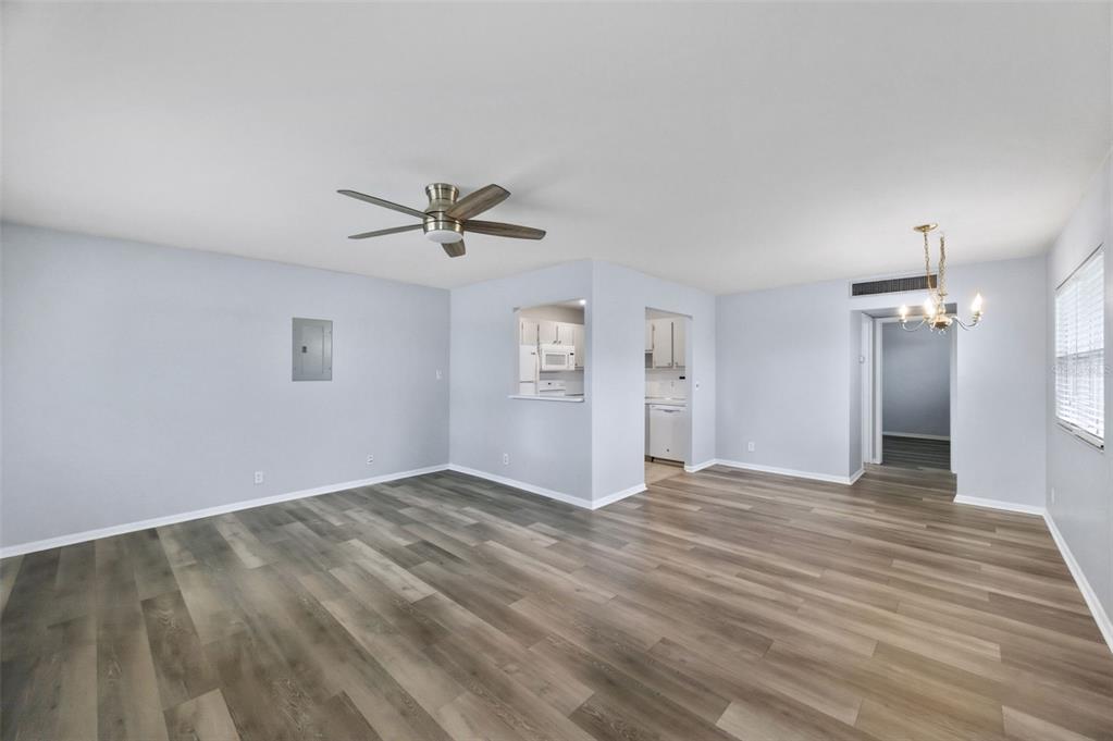 An open-concept living and dining area features light gray walls and wood-look vinyl flooring — 1801 BEDFORD TERRACE UNIT 227, SUN CITY CENTER, FL