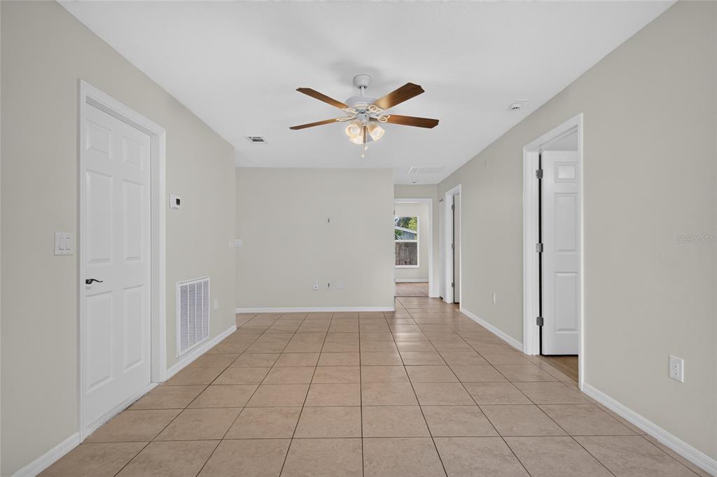A room with beige walls, tile flooring, a ceiling fan, and multiple white interior doors — 1004 17TH AVENUE W, BRADENTON, FL