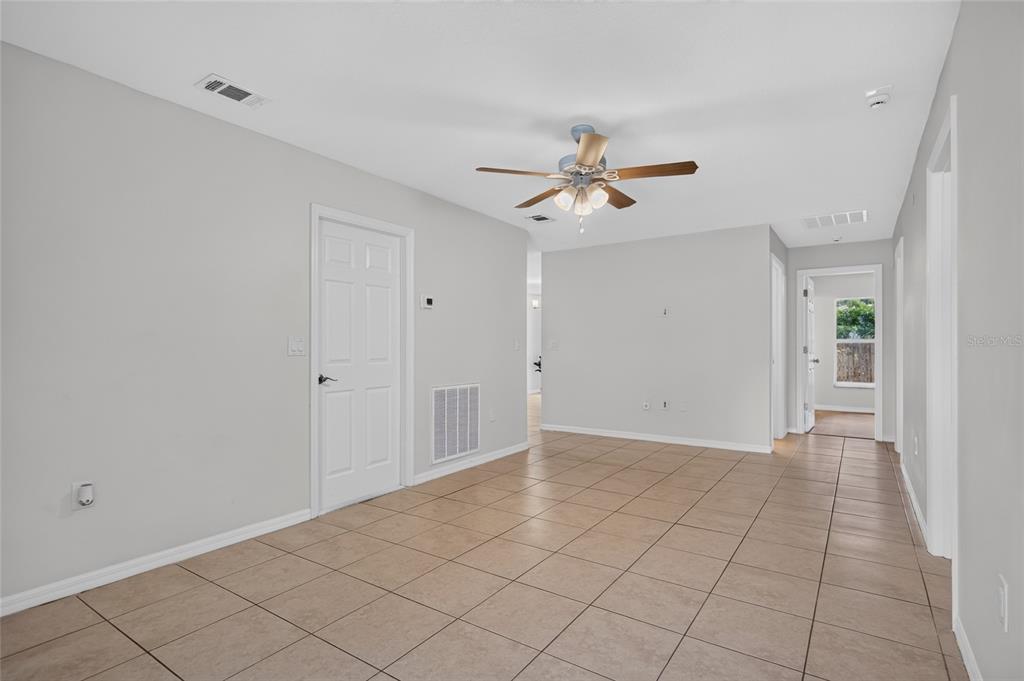 An interior view of a room with light gray walls, tile flooring, and a ceiling fan — 1004 17TH AVENUE W, BRADENTON, FL
