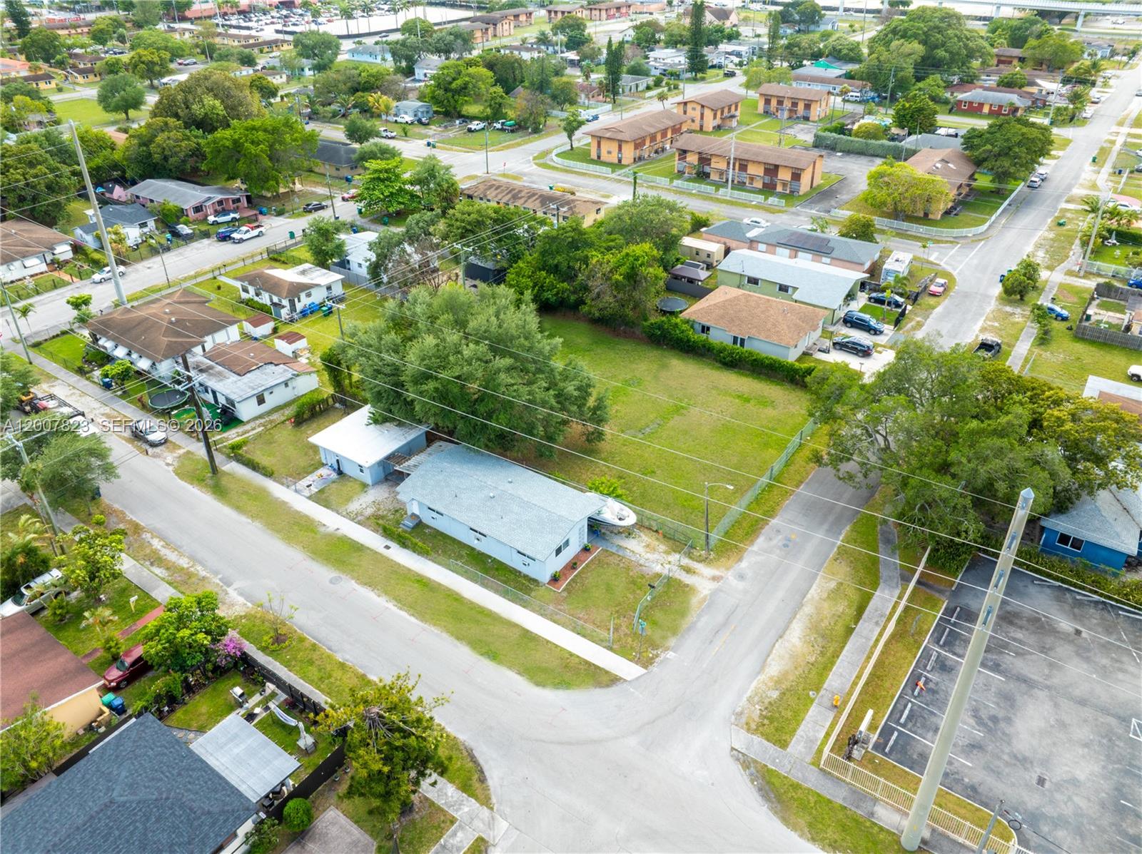 An aerial view shows a residential neighborhood with houses, a large vacant lot, and streets — 2406 NW 67th St, Miami FL 33147, MIAMI, FL