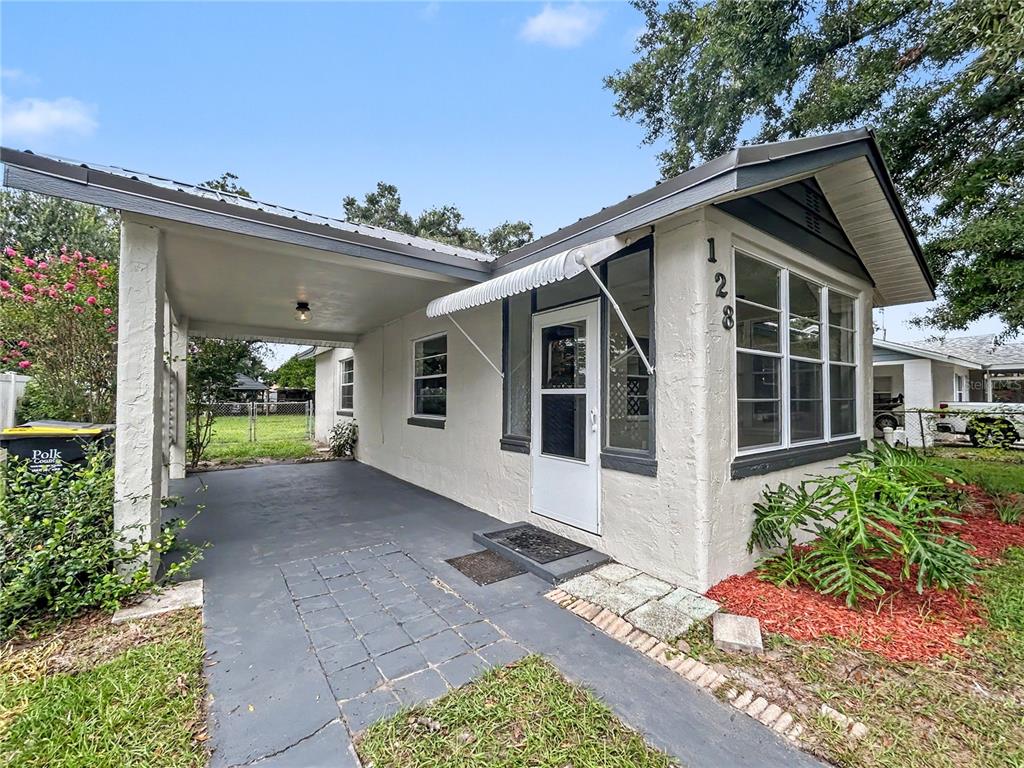 A single-story house with a carport, white stucco exterior, and a front-facing window — 128 CENTER STREET, WINTER HAVEN, FL