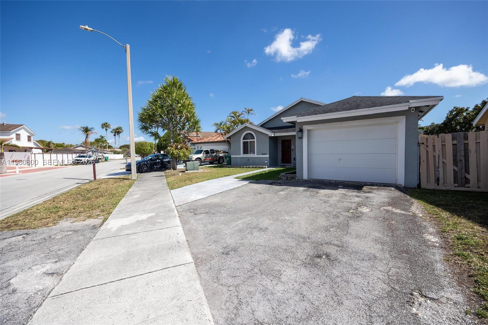 A gray single-story house features a white garage door, a driveway, and a sidewalk — 15260 SW 57th St, Miami FL 33193, MIAMI, FL
