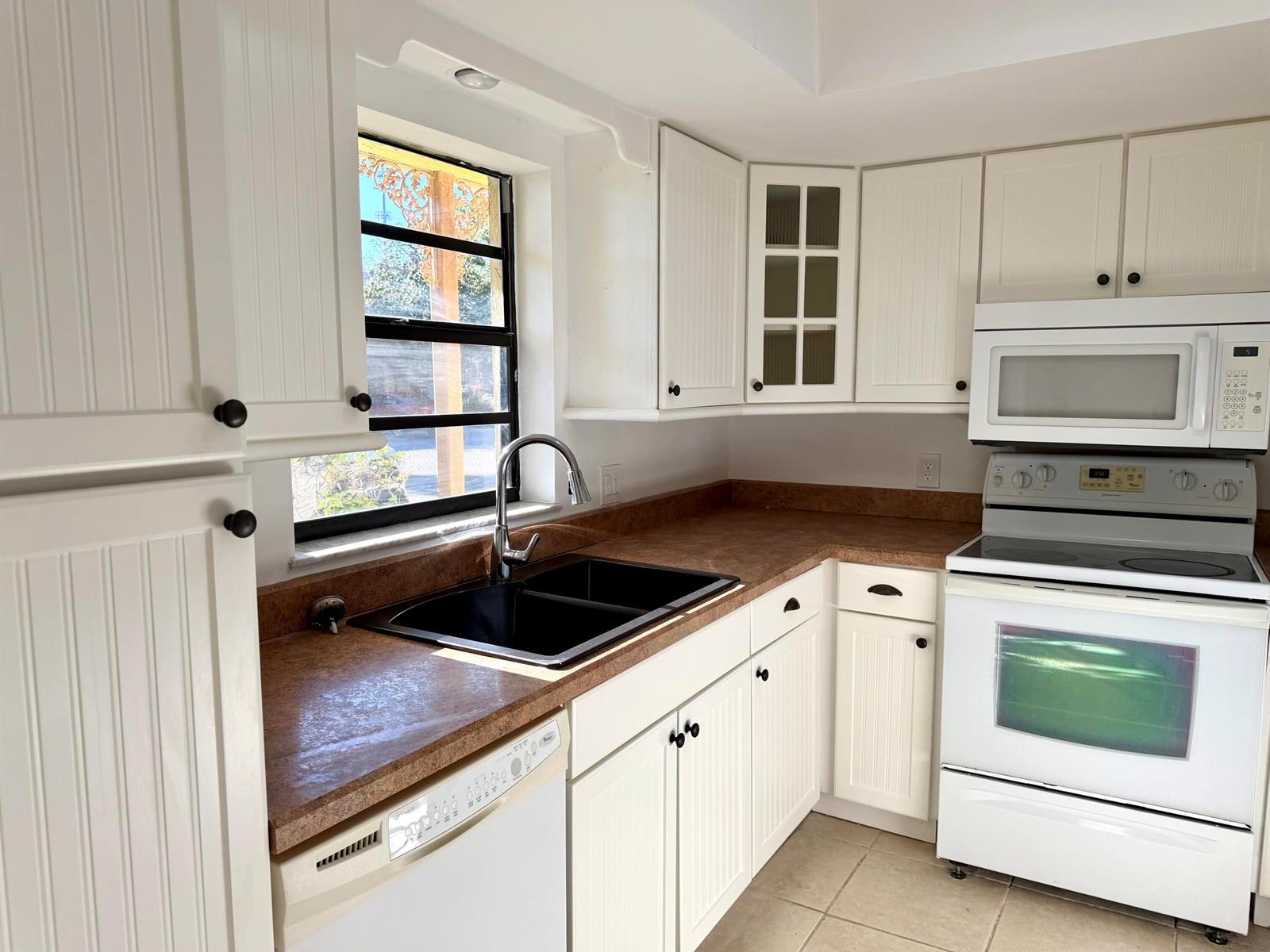 A kitchen with white beadboard cabinets, a black sink, and brown laminate countertops — 400 18th Street # B4, Vero Beach FL 32960, VERO BEACH, FL
