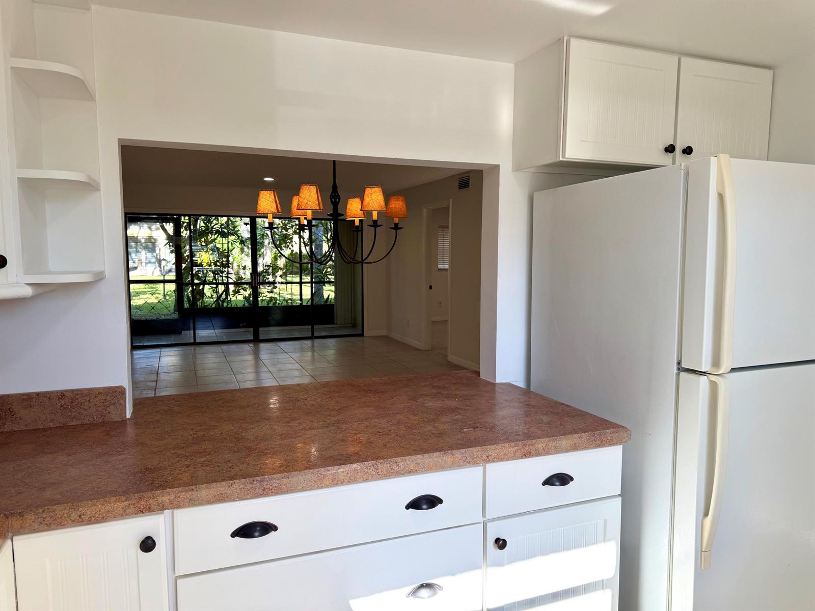 A kitchen with white cabinets, a brown countertop, and a pass-through window to a dining area — 400 18th Street # B4, Vero Beach FL 32960, VERO BEACH, FL