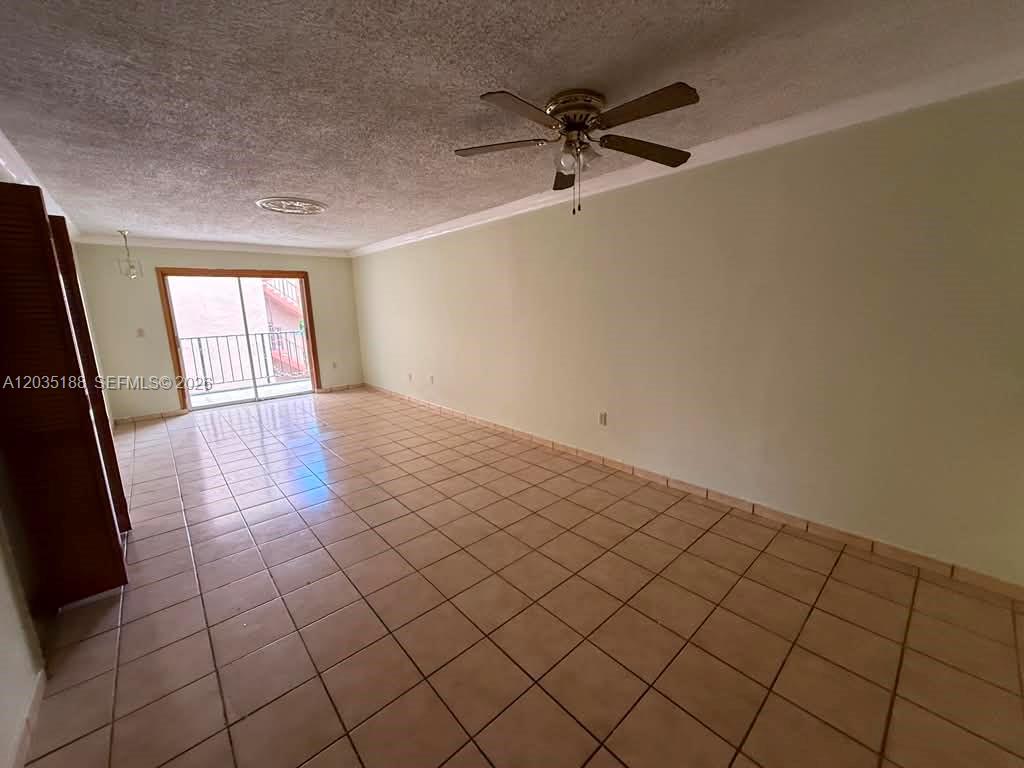 An empty room features light-colored tile flooring, a ceiling fan, and a sliding glass door — 6055 W 19th Ave # 305, Hialeah FL 33012, HIALEAH, FL