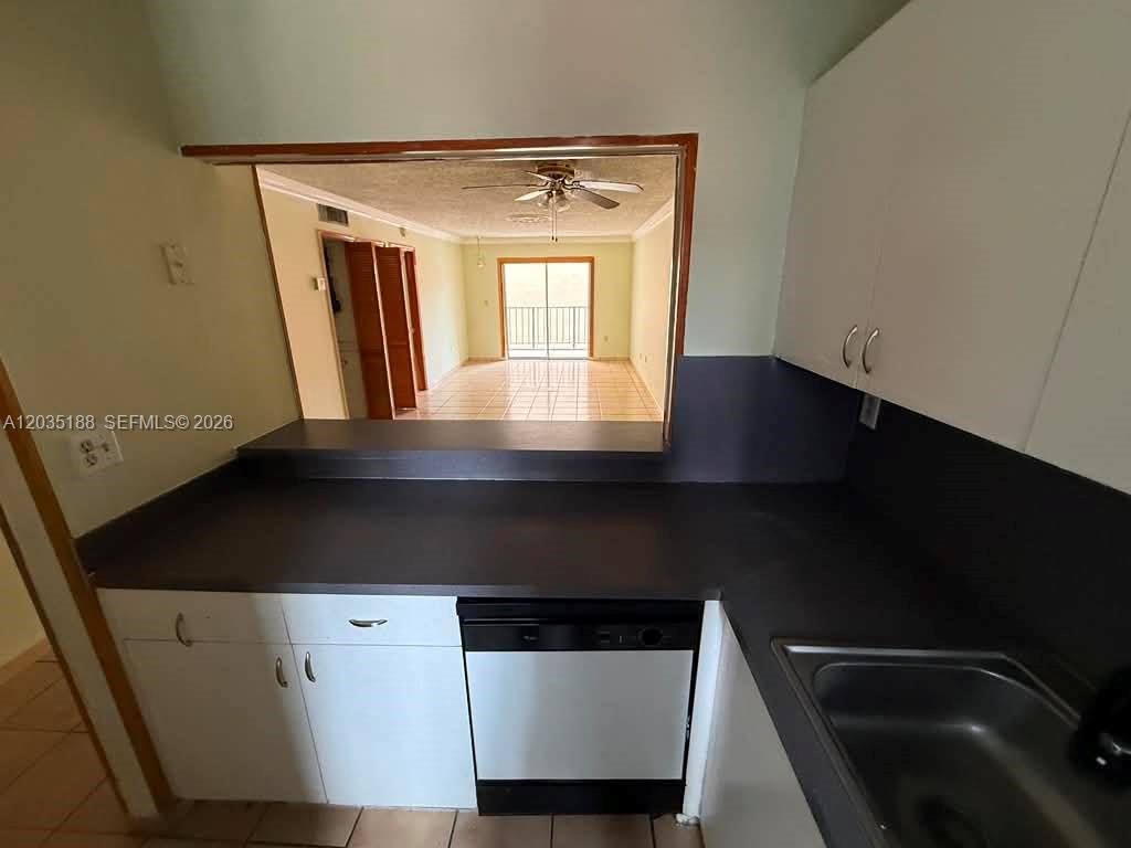A kitchen with white cabinets, dark countertops, and a pass-through window overlooking the living area — 6055 W 19th Ave # 305, Hialeah FL 33012, HIALEAH, FL