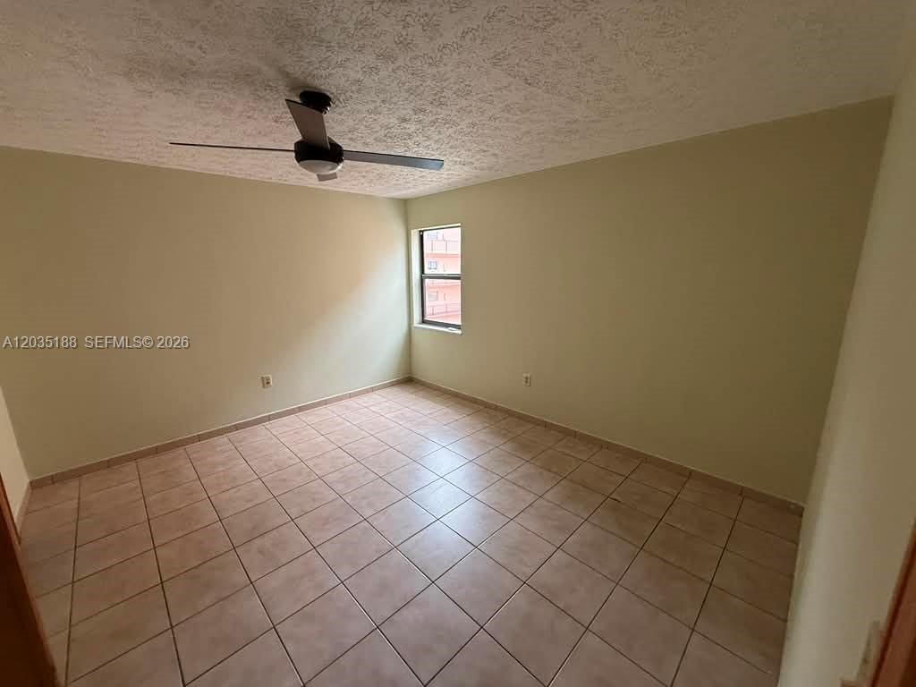 An empty bedroom features light-colored walls, a ceiling fan, and tiled flooring — 6055 W 19th Ave # 305, Hialeah FL 33012, HIALEAH, FL