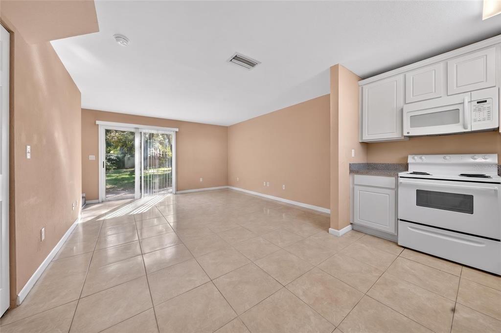 An open-concept kitchen and living area features beige tile flooring, peach walls, and white cabinetry — 4420 CARTER ROAD UNIT 41, ST AUGUSTINE, FL