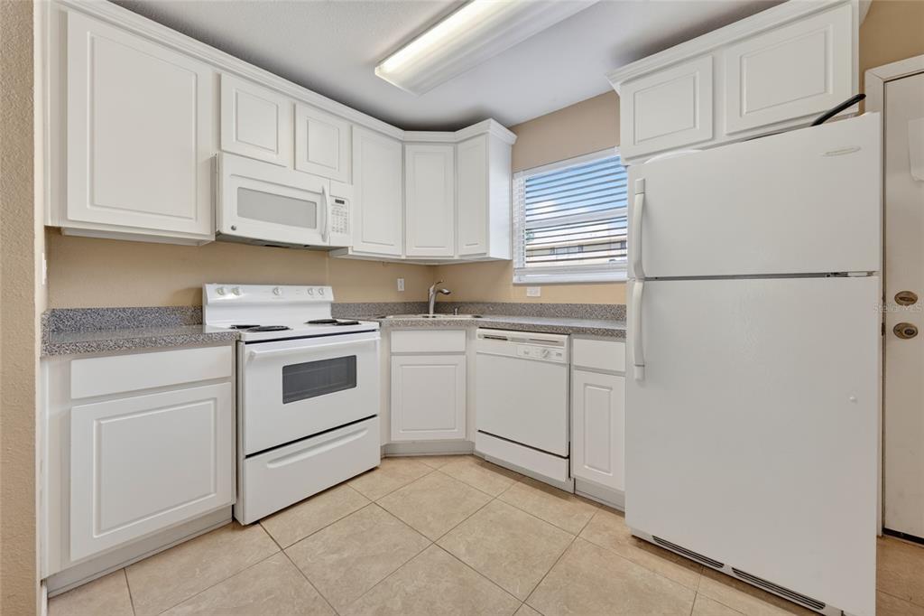 A kitchen with white cabinets, white appliances, and gray speckled countertops over tile flooring — 4420 CARTER ROAD UNIT 41, ST AUGUSTINE, FL
