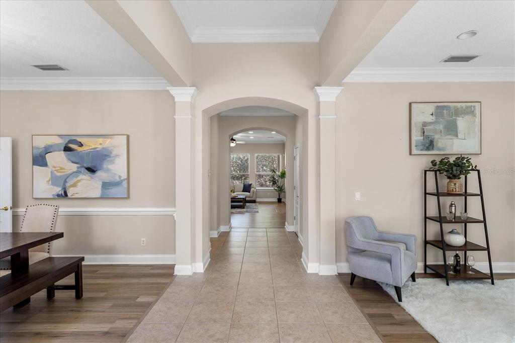 A tiled hallway leads through an arched entryway into a living area with wood flooring — 25516 HAWKS RUN LANE, SORRENTO, FL