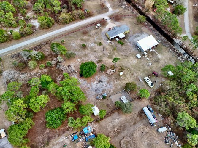 An aerial view shows a rural property with multiple buildings, trailers, and scattered trees — 220 N PALOMINO ST, Clewiston FL 33440, CLEWISTON, FL