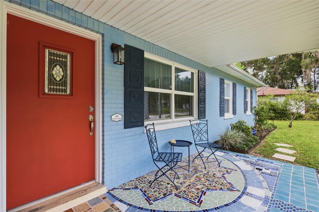 A living room with an orange chair, a gallery wall, and a view into a dining area — 912 E ARIZONA AVENUE, DELAND, FL