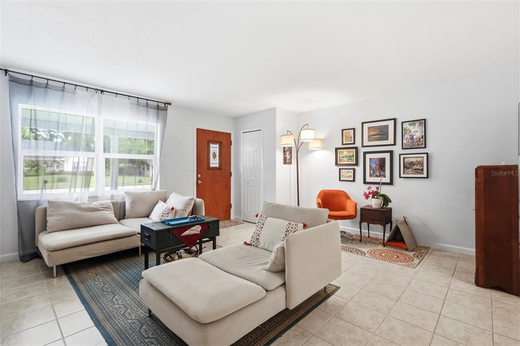 A living room features a white sectional sofa, a wall-mounted TV, and an orange chair — 912 E ARIZONA AVENUE, DELAND, FL