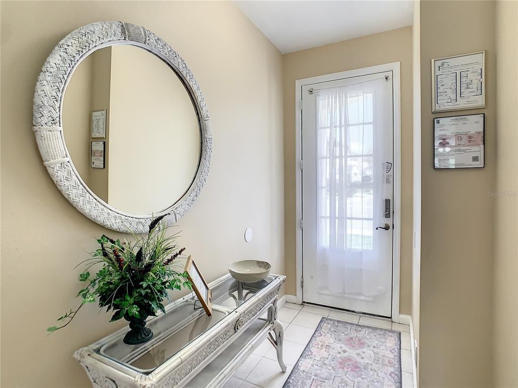 An entryway features a round mirror, a glass-topped console table, and a white front door — 2356 SILVER PALM DRIVE, KISSIMMEE, FL