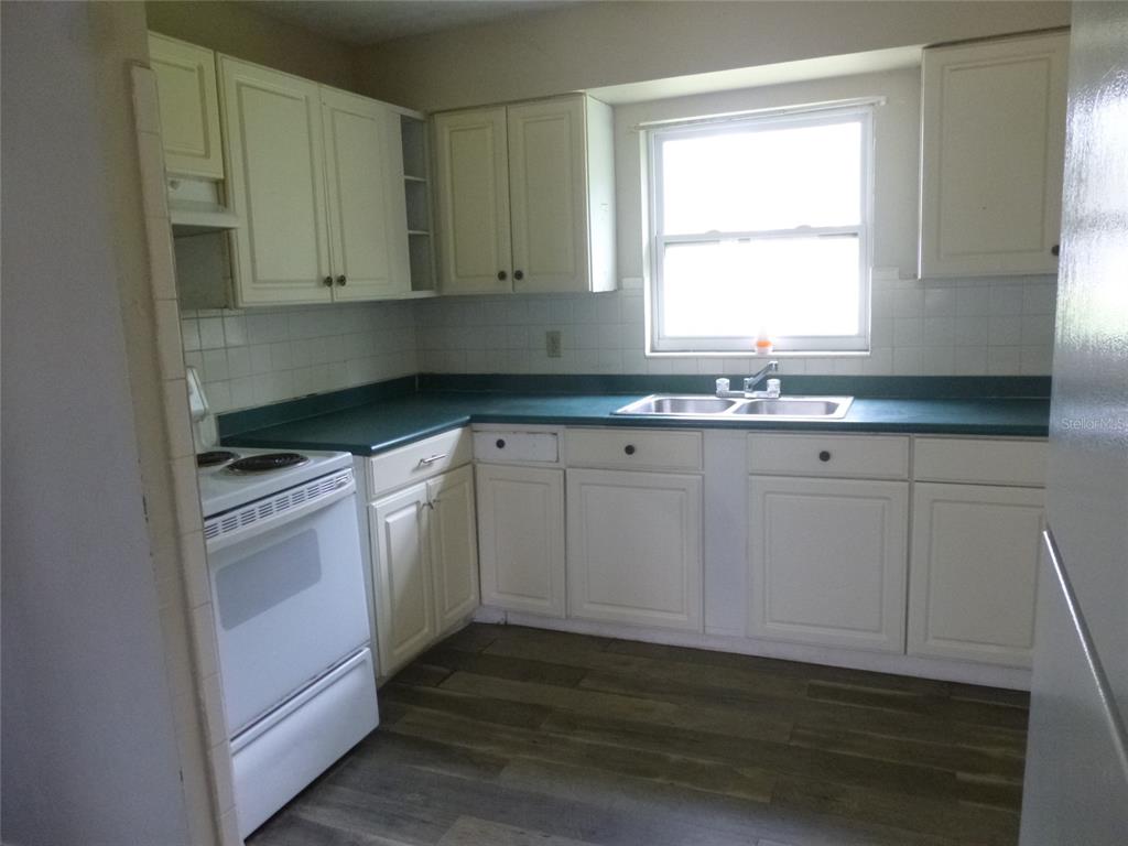 A kitchen features white cabinets, a green countertop, a white stove, and wood-look flooring — 12 HWY 630 W, FROSTPROOF, FL
